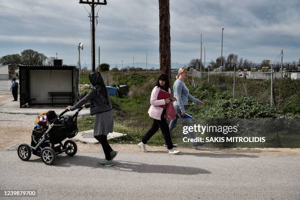 Ukrainian refugees walks next to a migrant woman from Afghanistan with her baby at Serres refugee camp, northern Greece, on April 4, 2022. - For more...