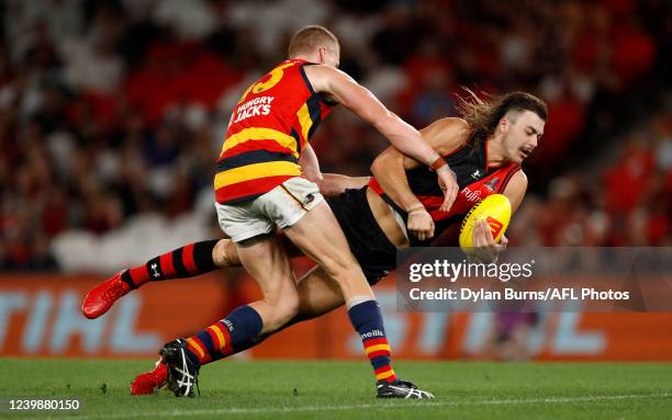 Sam Draper of the Bombers is tackled by Reilly O'Brien of the Crows during the 2022 AFL Round 04 match between the Essendon Bombers and the Adelaide...