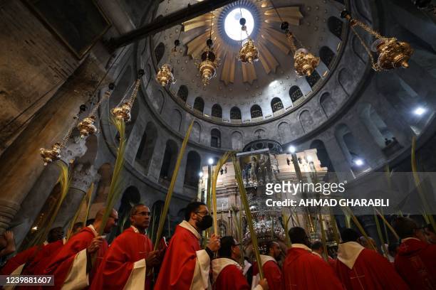 Roman Catholic clergy carry palm branches as they circle the aedicule during the Palm Sunday procession at the Church of the Holy Sepulchre in...
