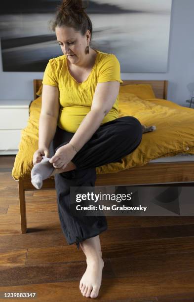 In this photo illustration a pregnant woman tries to put on a sock on April 08, 2022 in Bonn, Germany.