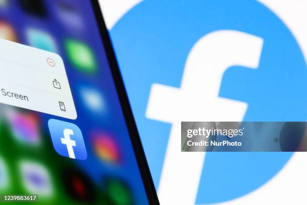 Facebook icon displayed on a phone screen and Facebook logo displayed on a screen in the background are seen in this illustration photo taken in...