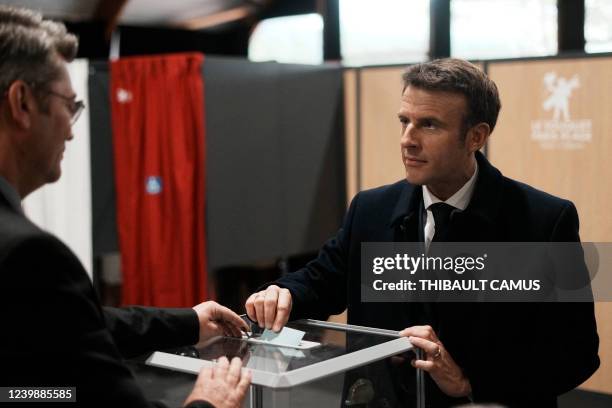 France's President and LREM party presidential candidate Emmanuel Macron interacts with an electoral official as he casts his ballot for the first...