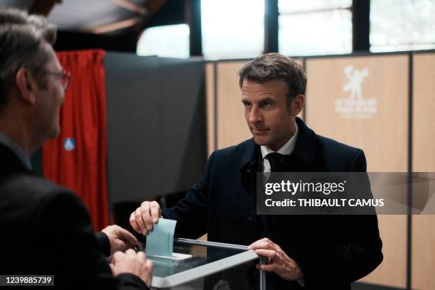 France's President and LREM party presidential candidate Emmanuel Macron interacts with an electoral official as he casts his ballot for the first...