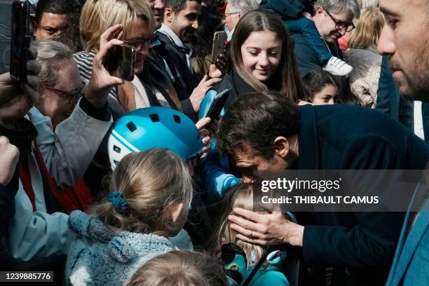 French President and LREM party presidential candidate Emmanuel Macron kisses a young child as he greets onlookers ahead of casting his ballot for...