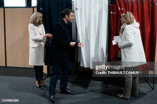 France's President and LREM party presidential candidate Emmanuel Macron , next to his wife Brigitte Macron , speaks to a resident before voting for...