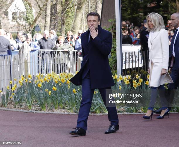 French President and candidate for re-election Emmanuel Macron and his wife Brigitte Macron greet people after voting for the first round of the...