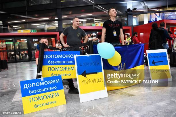 Volunteers with signs welcome Ukrainian refugees as they arrive at the Tijuana airport to help them on their journey to the United States after...