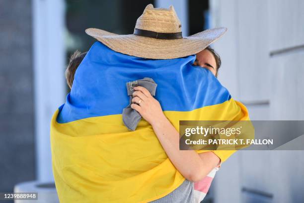 Oleksii Yeromin, wrapped in a Ukrainian flag, hugs a Ukrainien refugee as they cross the San Ysidro PedWest port of entry along the US-Mexico border...