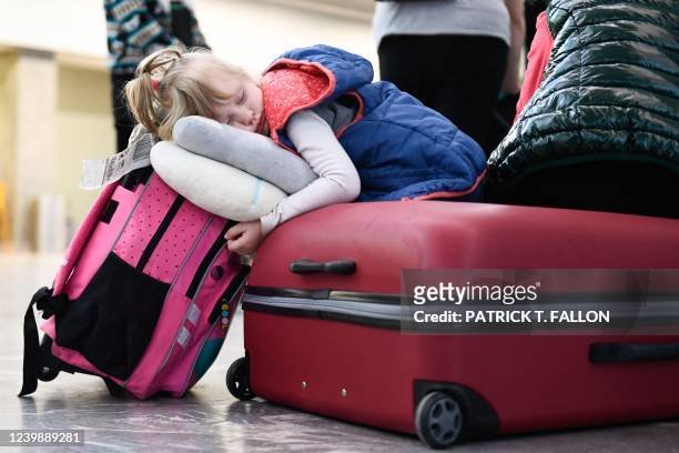 Anna Kuts sleeps on a suitcase after arriving with her family at the Tijuana airport where they are met by volunteers to help them on their journey...
