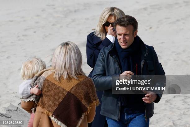 France's President and LREM party presidential candidate Emmanuel Macron and his wife Brigitte Macron meet people during a walk on a beach of the...