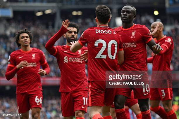 Liverpool's Portuguese striker Diogo Jota celebrates after scoring the equalising goal with Liverpool's Egyptian midfielder Mohamed Salah and...
