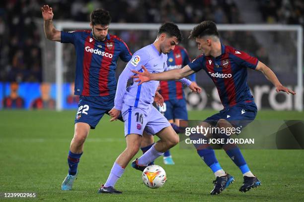 Barcelona's Spanish midfielder Pedri vies with Levante's Spanish midfielder Gonzalo Melero and Levante's Spanish midfielder Pepelu during the Spanish...