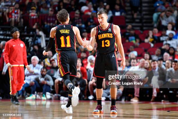 Trae Young hi-fives Bogdan Bogdanovic of the Atlanta Hawks during the game against the Houston Rockets on April 10, 2022 at the Toyota Center in...