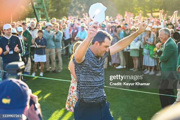 Scottie Scheffler raises his arms and celebrates his three stroke victory after walking off the 18th hole green during the final round of the Masters...