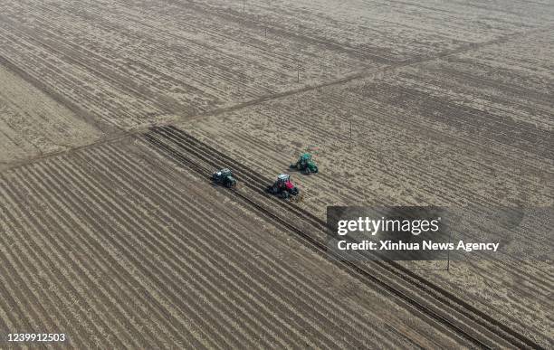 Aerial photo taken on April 9, 2022 shows farmers working on agricultural machinery at a field in Cainiu Town of Tieling County in northeast China's...