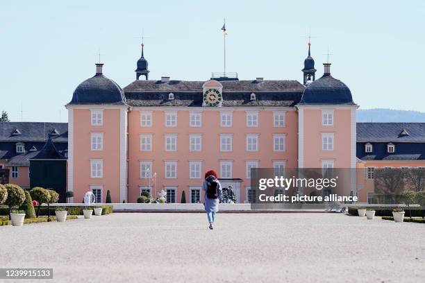 April 2022, Baden-Wuerttemberg, Schwetzingen: A visitor walks through the grounds of the palace garden in front of Schwetzingen Palace. The palace...