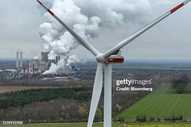 Cooling towers emit vapor at the Niederaussem lignite fueled power station, operated by RWE AG, beyond a wind turbine in Bergheim Niederaussem,...