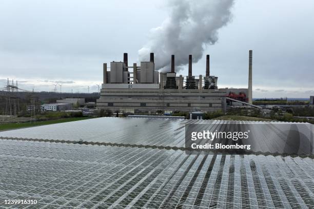 Cooling towers emit vapor at the Neurath lignite fueled power station, operated by RWE AG, beyond green houses in Grevenbroich, Germany, on Friday,...