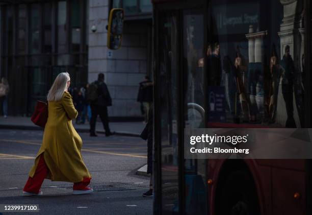 Morning commuter crosses a street in front of a bus in the City of London, U.K., on Monday, April 11, 2022. The labor market data for February will...