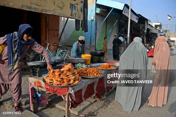 Afghan burqa-clad women buy fast food from a roadside stall during the holy fasting month of Ramadan in Kandahar on April 11, 2022.