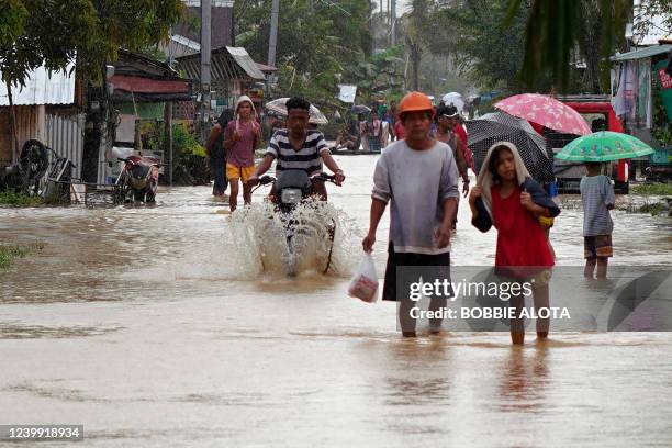 Residents and a motorist wade through a flooded street after heavy rains brought about by Tropical storm Agaton in Abuyog town, Leyte province,...