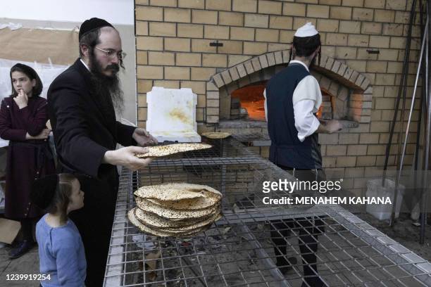 An Ultra-Orthodox Jewish piles up freshly baked Matzoth at a bakery in the central Israeli city of Beit Shemesh, on April 11, 2022. - Religious Jews...