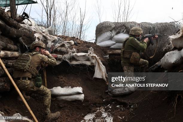 Ukrainian soldiers shoot with assault rifles in a trench on the front line with Russian troops in Lugansk region on April 11, 2022.