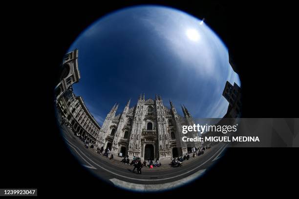 Photograph taken with a fisheye lens on April 11, 2022 shows people passing by the Duomo di Milano on Duomo square, in central Milan.