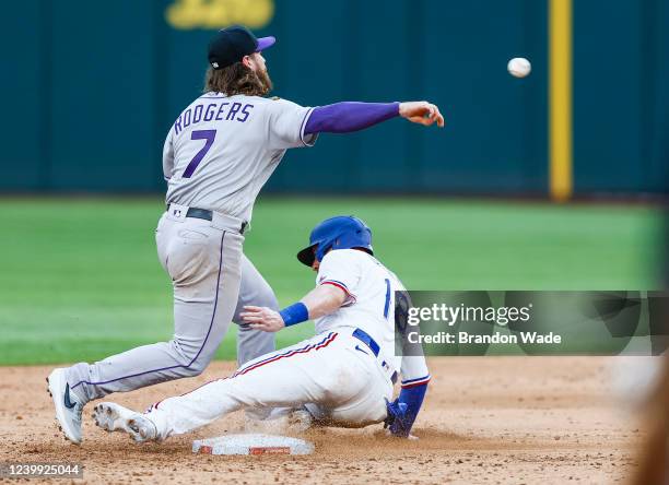 Mitch Garver of the Texas Rangers slides into second base as Brendan Rodgers of the Colorado Rockies throws to first in the 10th inning of the home...