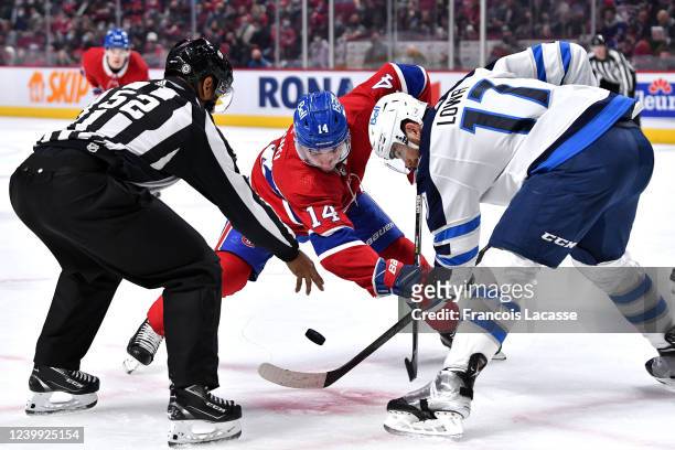 Nick Suzuki of the Montreal Canadiens faces off against Adam Lowry of the Winnipeg Jets in the NHL game at the Bell Centre on April 11, 2022 in...