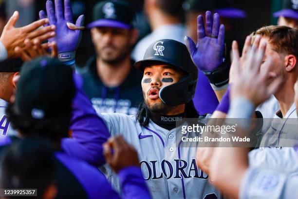 Connor Joe of the Colorado Rockies is congratulated by teammates after hitting a solo home run in the 10th inning against the Texas Rangers in the...