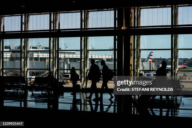 American Airlines aircrafts are seen in the background behind travelers passing through Ronald Reagan Washington National Airport in Arlington,...