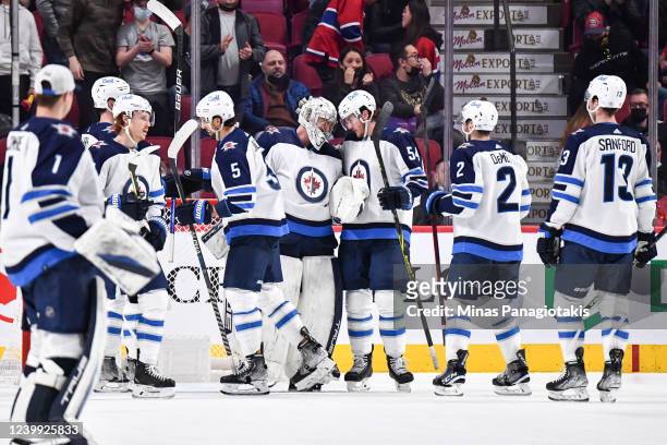 Goaltender Connor Hellebuyck of the Winnipeg Jets and teammate Dylan Samberg celebrate their victory against the Montreal Canadiens at Centre Bell on...