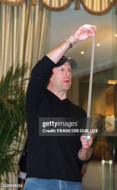 L'acteur américain Bruce Willis joue avec un rouleau de scotch, le 09 décembre 1999 dans un grand hôtel parisien, lors d'une séance photo pour la...