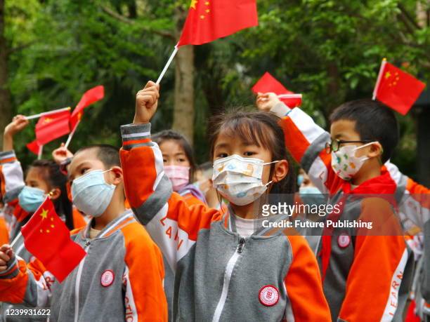 Mask-clad children wave national flags in a gathering to celebrate the lifting of the lockdown imposed on their residential block in Suining in...