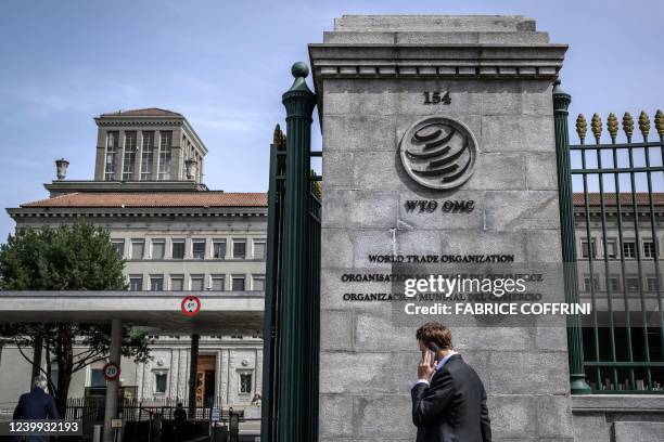 Man phones with his mobile while entering the World Trade Organization headquarters in Geneva on April 12, 2022. WTO chief said that diplomatic...