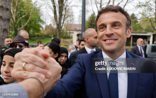 France's President and French liberal party La Republique en Marche candidate to his succession Emmanuel Macron greets people outside the Alister...