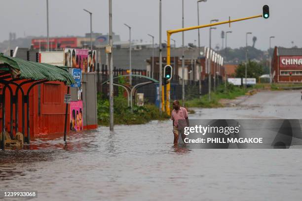 Man walks towards food stalls following heavy rains and winds in Durban, on April 12, 2022. - At least five people have been killed in floods and...