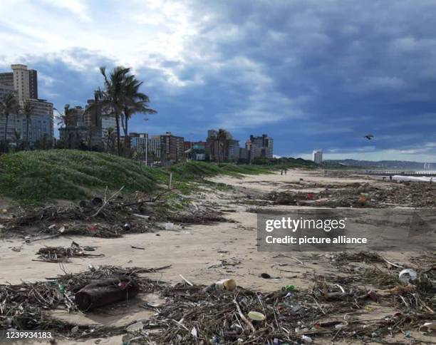 April 2022, South Africa, Durban: Dark clouds pass over the beach, where abundant garbage washed up after unusually heavy rainfall. The population...