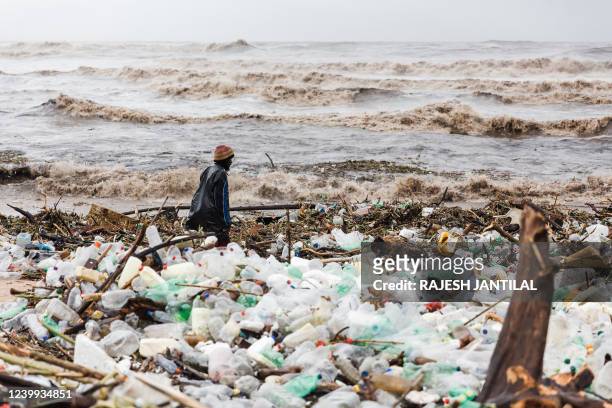 Man is seen searching through debris at the Blue Lagoon beach following heavy rains and winds in Durban, on April 12, 2022. - At least 45 people have...
