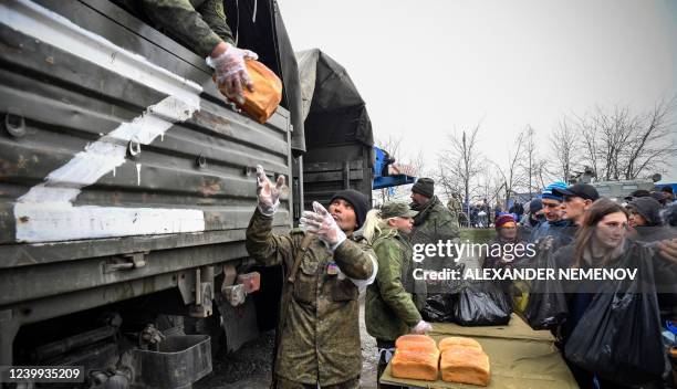 Russian soldiers and volunteers distribute bread in Mariupol on April 12 as Russian troops intensify a campaign to take the strategic port city, part...