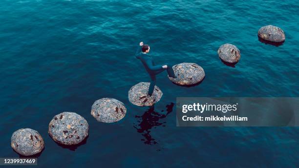 het vermijden van valkuilen in de carrière van een zakenman die op springstenen loopt - pitfall stockfoto's en -beelden