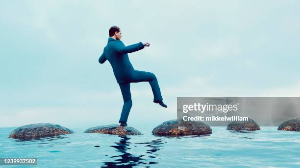 de zakenman gebruikt stapstenen om zorgvuldig vooruit te gaan - pitfall stockfoto's en -beelden