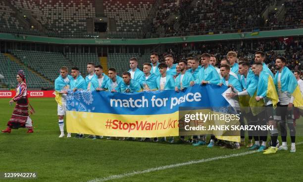 The teams line up behind a banner prior to the solidarity football match "Match for peace" between Dynamo Kyiv and Legia Warszawa in Warsaw on April...