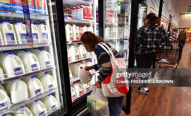 Person pulls out a gallon of milk as people shop at a grocery store in Monterey Park, California, on April 12, 2022. - Americans paid more for...