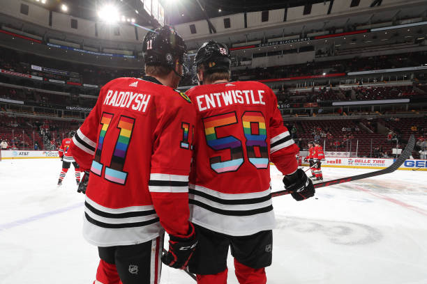 Taylor Raddysh and MacKenzie Entwistle of the Chicago Blackhawks warm up with rainbow colors on their jersey in honor of Pride Night, prior to the...