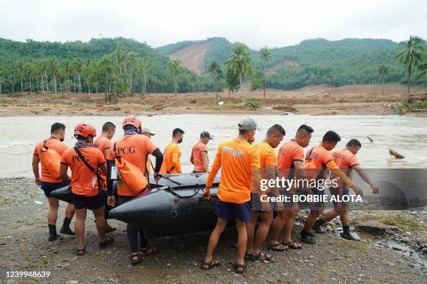 Rescuers carry an inflatable boat towards a river as they attempt to reach the landslide-hit village of Kantagnos in Baybay town, Leyte province on...