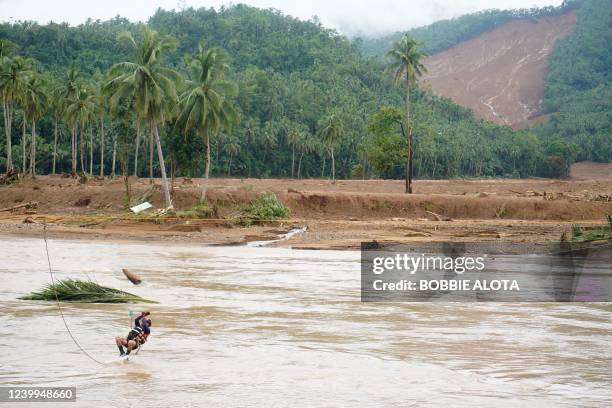 Rescuer crosses a river using a zip line in an attempt to reach the landslide-hit village of Kantagnos in Baybay town, Leyte province on April 13...