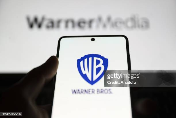 In this photo, illustration the logo of Warner Bros. Is displayed on phone screen and the logo of Warner Media is displayed on computer screen back...