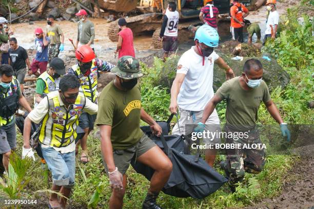 Rescue workers carry body bags containing the retrieved bodies of victims of a landslide that slammed the village of Bunga in Baybay town, Leyte...
